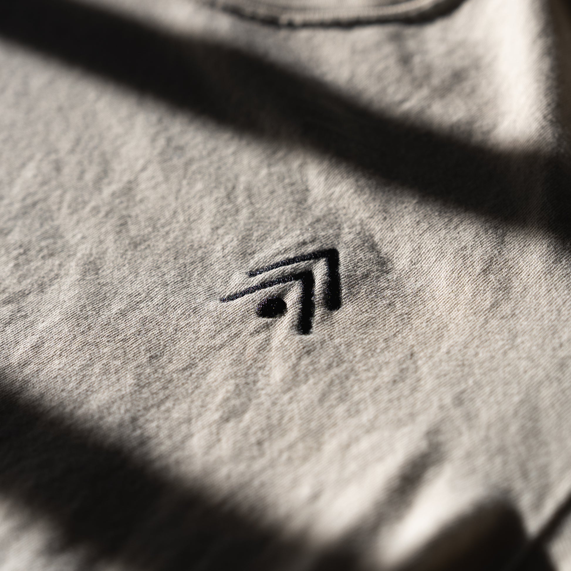 Close-up of a textured ivory fabric with an embroidered logo.