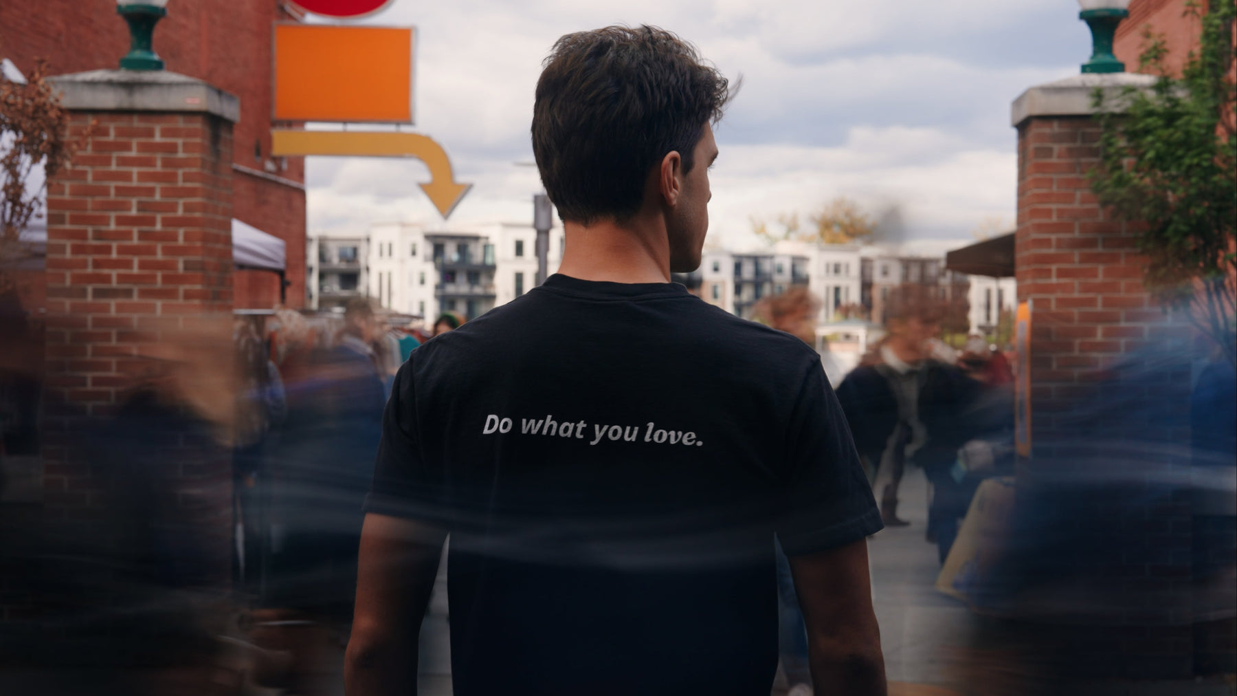 Person wearing a black t-shirt with 'Do what you love.' text in an urban setting.