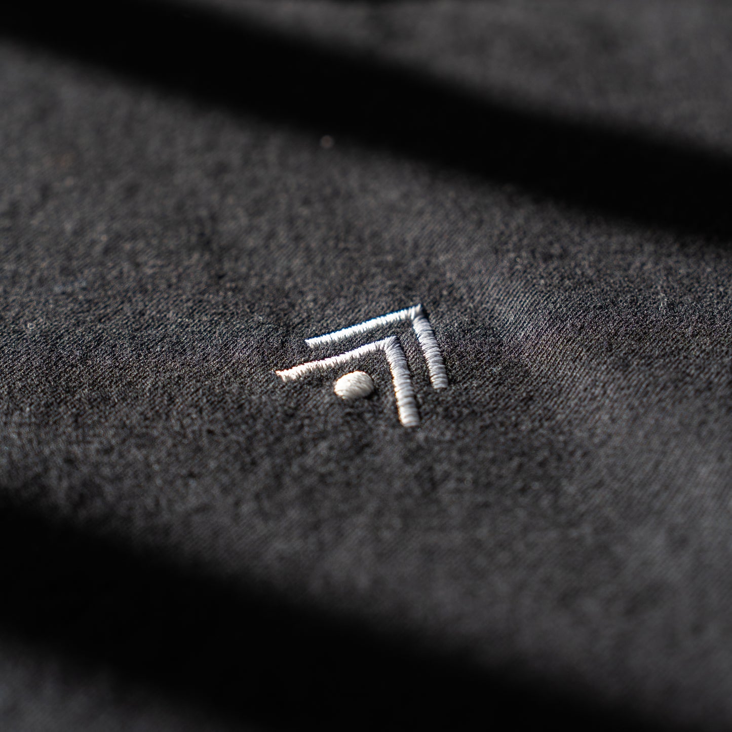 Close-up of a textured black fabric with an embroidered logo.
