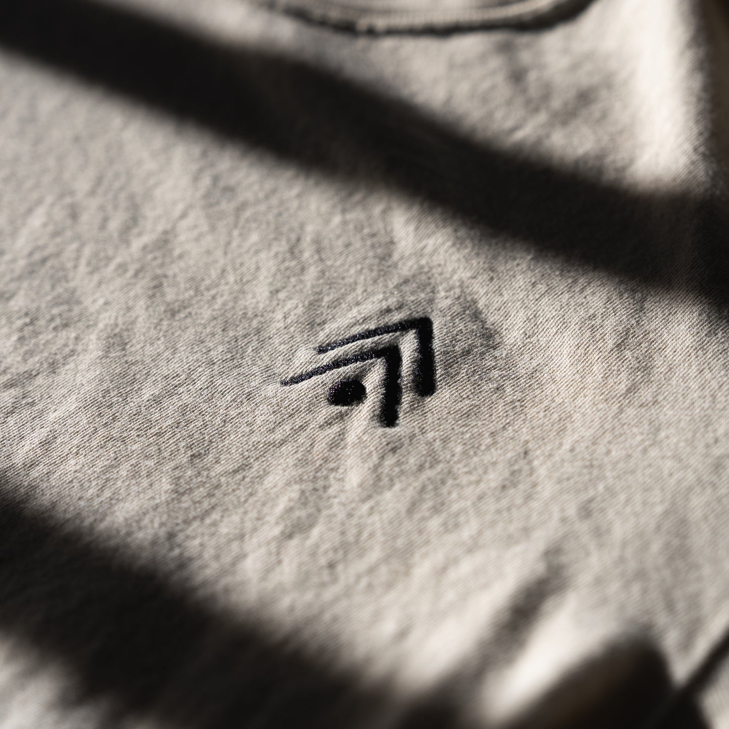 Close-up of a textured ivory fabric with an embroidered logo.